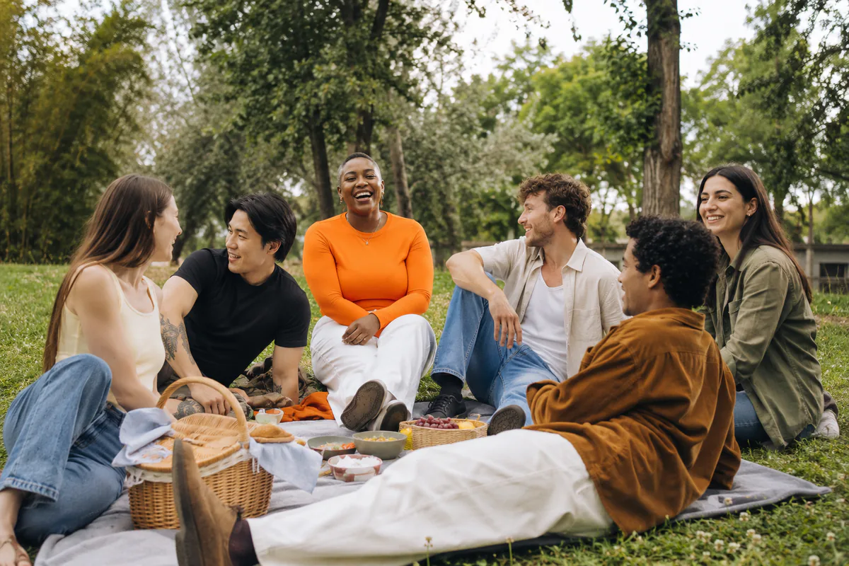 A group of friends sits together at a picnic while one person remains easy to identify.